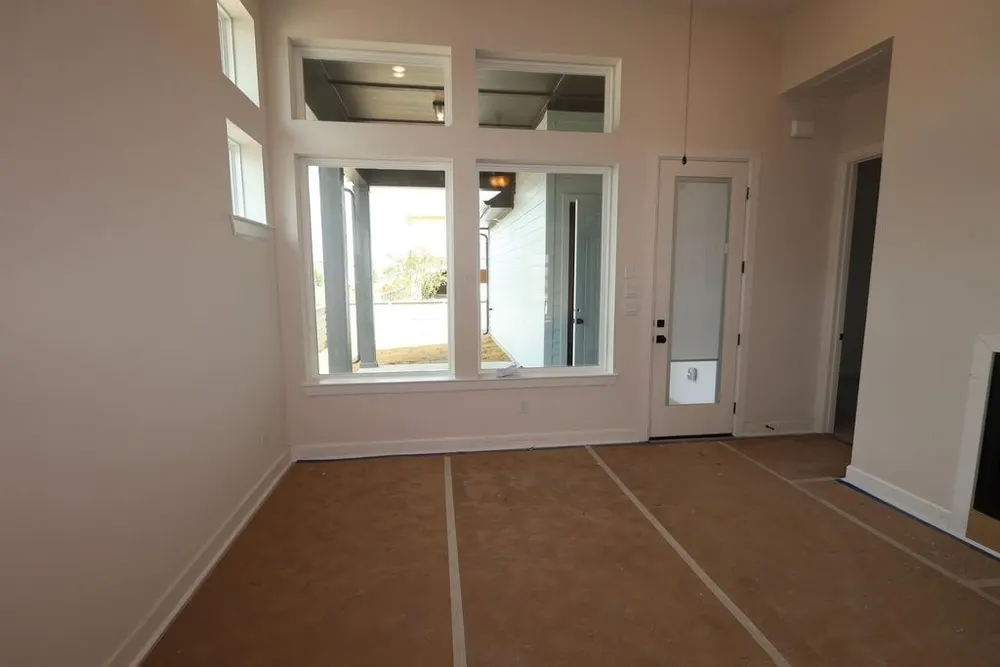 Before: the same living room empty, with protective floor covering and bare walls around the tall windows